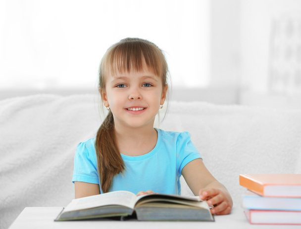 Little girl sitting on sofa with book - Foto, imagen