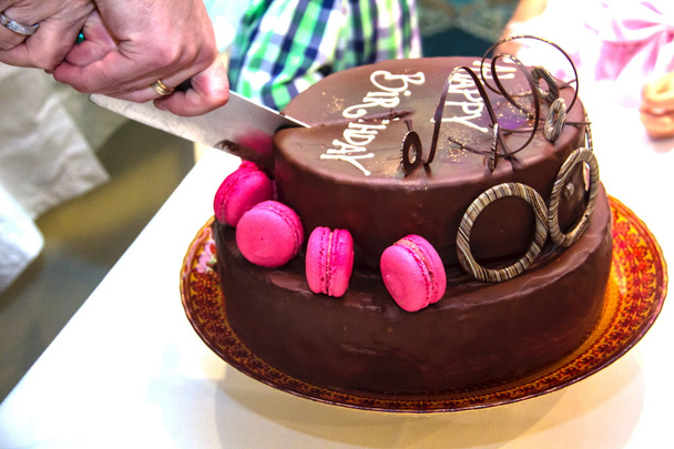 Cortando o belamente decorado um bolo de chocolate festivo com a inscrição Feliz Aniversário em pedaços
 - Foto, Imagem