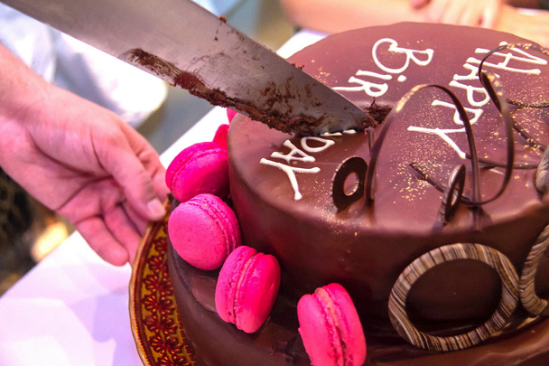 Cortar la hermosa decoración de un pastel de chocolate festivo con la inscripción Feliz Cumpleaños en pedazos
 - Foto, Imagen