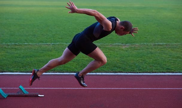 Athletic man start on track - Foto, afbeelding