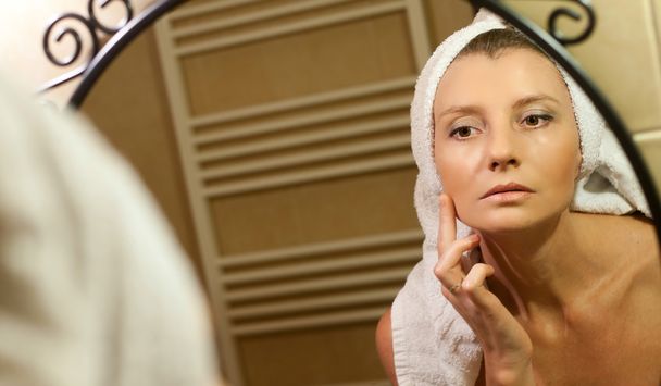Középkorú nő arcát a fürdőszobában tükör ellenőrzése után sho - Fotó, kép