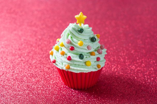 Cupcake de árvore de Natal com um fundo de brilho vermelho
 - Foto, Imagem