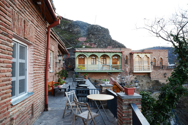 die Außenterrasse mit Tischen. Wohnhäuser am Hang im alten Tiflis - Foto, Bild