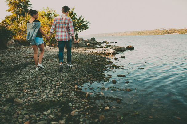Teenage loving couple walking together by a lake - Fotoğraf, Görsel