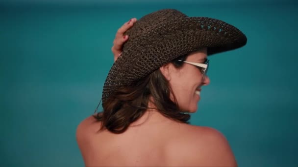 Beautiful woman smiling in front of ocean with beach hat - Video, Çekim