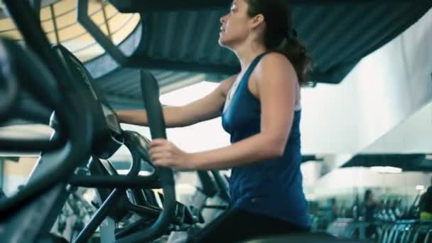 Kobieta na maszyny eliptyczne w siłowni - Materiał filmowy, wideo