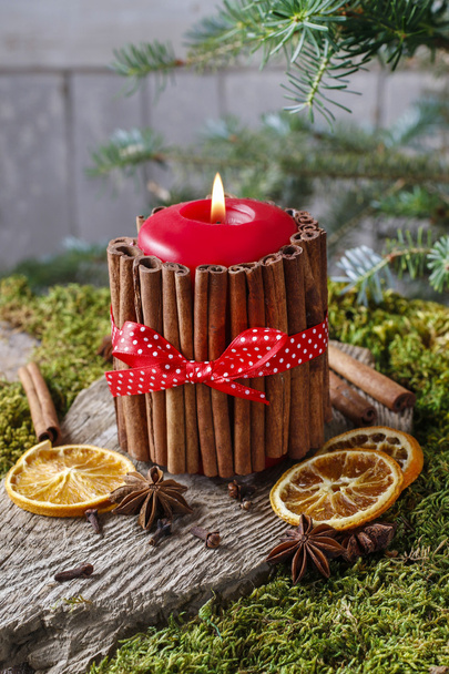 Candle decorated with cinnamon sticks and dried fruits around - Zdjęcie, obraz