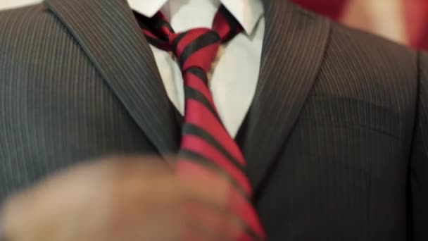 Close-up van jonge man handen als hij zijn das bevestigt - Video