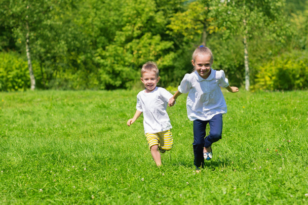 Girl and boy running on the grass - Foto, afbeelding