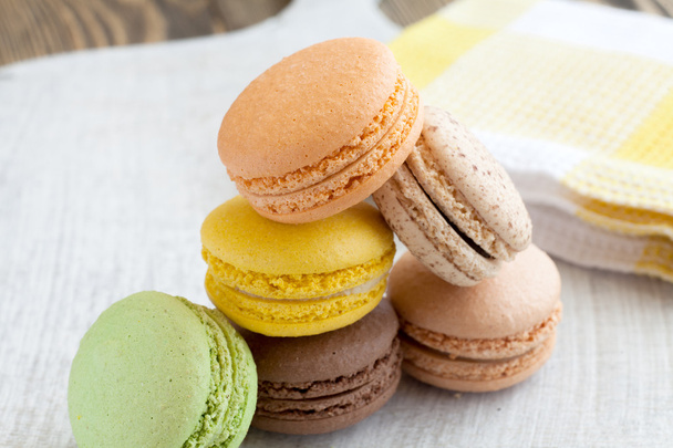 colored macaroon on a wooden background - 写真・画像
