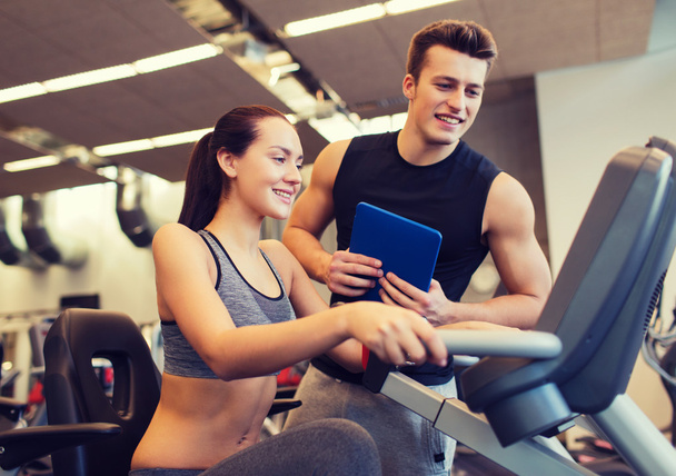 happy woman with trainer on exercise bike in gym - Foto, immagini