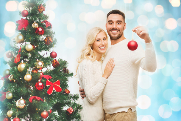 happy couple decorating christmas tree at home - 写真・画像