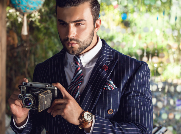 Young fashionable man with retro camera. - 写真・画像