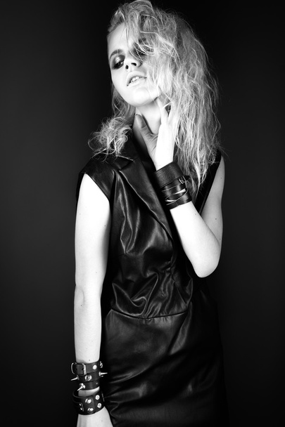 Daring girl model in black leather dress, style of rock, dark make-up, wet hair and bracelets on her arms. - Zdjęcie, obraz