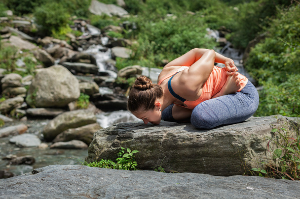 Young woman does yoga oudoors at waterfall - Photo, Image