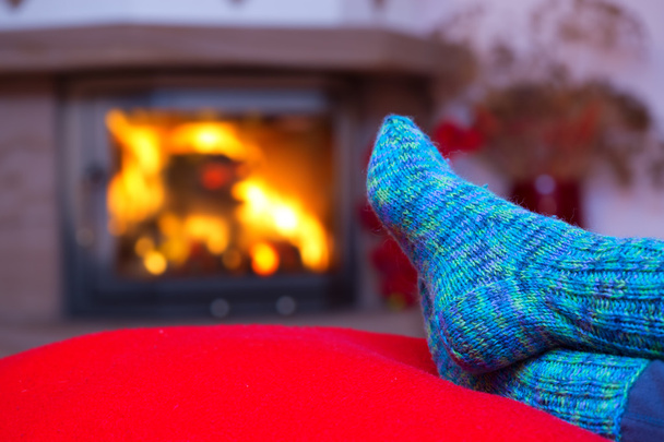 Feet in woollen blue socks by the fireplace. - Fotó, kép