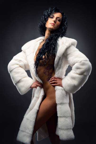 Gorgeous sexy brunette wearing white fur coat posing indoors - Fotó, kép
