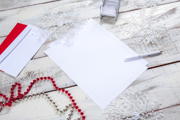 The blank sheet of paper on the wooden table with a pen and  Christmas decorations. Christmas mockup concept - 写真・画像