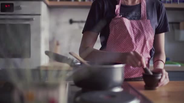 Young girl in apron preparing food in kitchen - Filmati, video