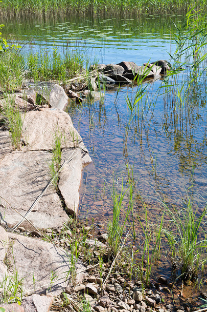 Lake rand met rode granieten rotsen - Foto, afbeelding