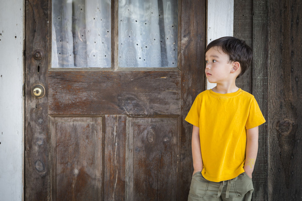 Melancholy Mixed Race Boy Standing In Front of Door - 写真・画像