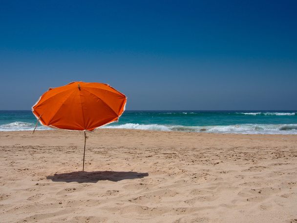 Sombrilla naranja en la playa
 - Foto, imagen