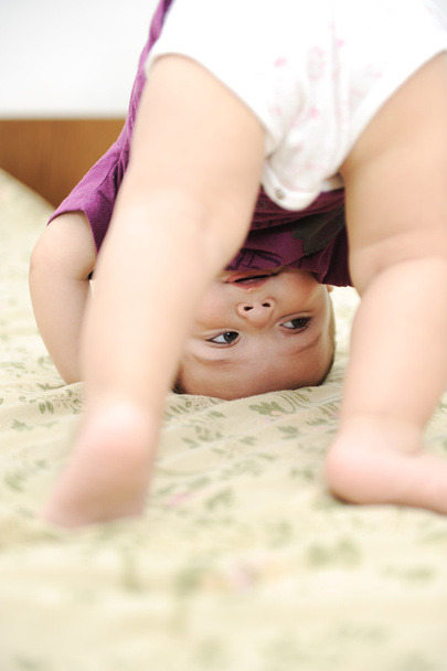 Baby boy playing upside down in bedroom - Foto, immagini