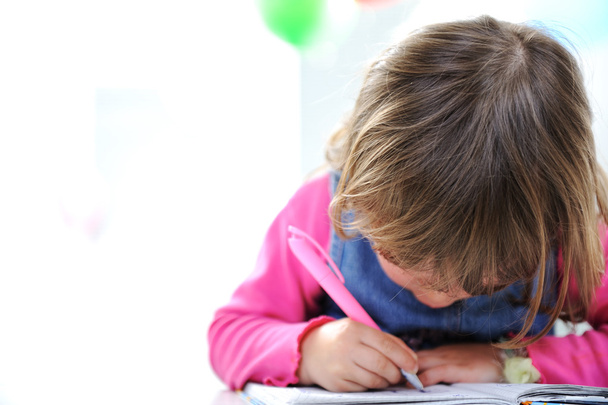 Маленькая милая блондинка девочка рисует карандашом на бумаге, большой спа-центр
 - Фото, изображение