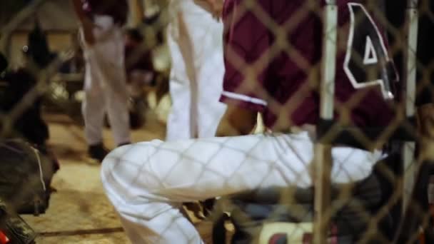 Joven jugador de béisbol sentado dentro de un dugout y jugando con una pelota
 - Metraje, vídeo