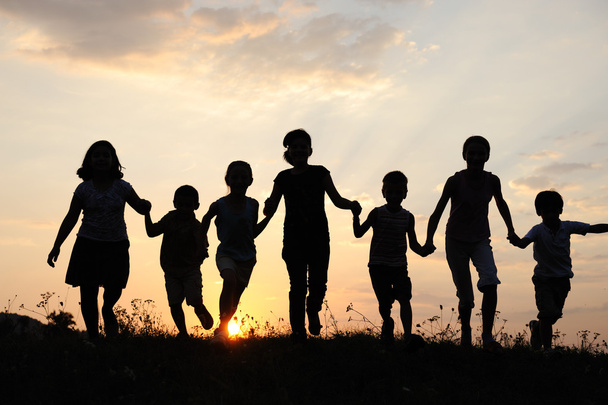 Silhouette, group of happy children playing on meadow, sunset, summertime - Foto, immagini