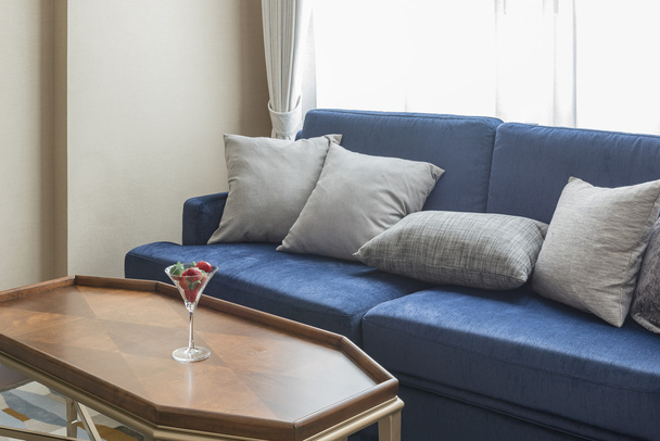 Blaues Luxussofa mit grauen Kissen und Holztisch - Foto, Bild