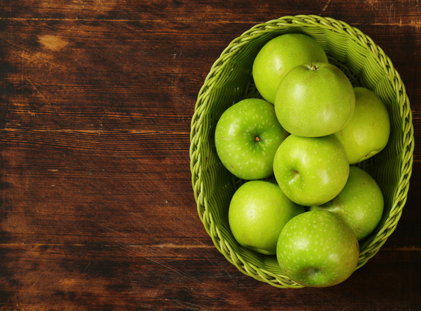 Fresh organic green apples in a basket on a wooden background - Photo, Image
