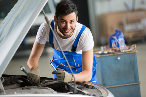 smiling mechanic working on engine - Фото, изображение