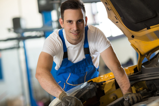 Smiling mechanic working on engine - Foto, imagen
