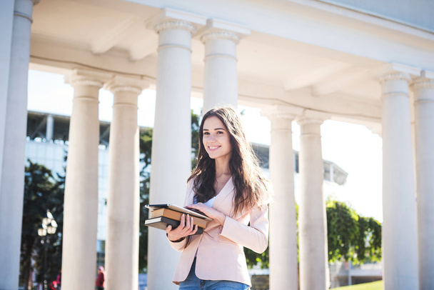young caucasian female student with books and tablet on campus, student study in campus area - Foto, imagen