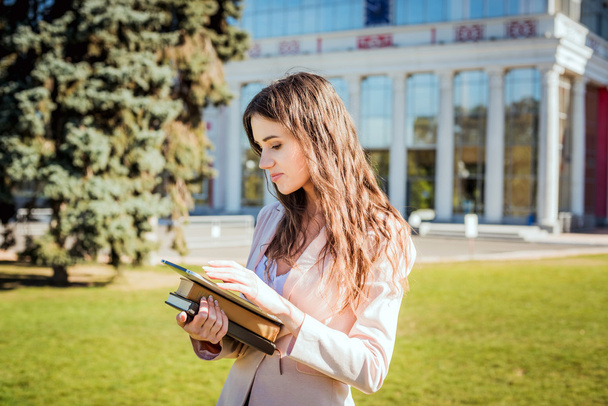 young caucasian female student with books and tablet on campus, student study in campus area - Foto, Imagem