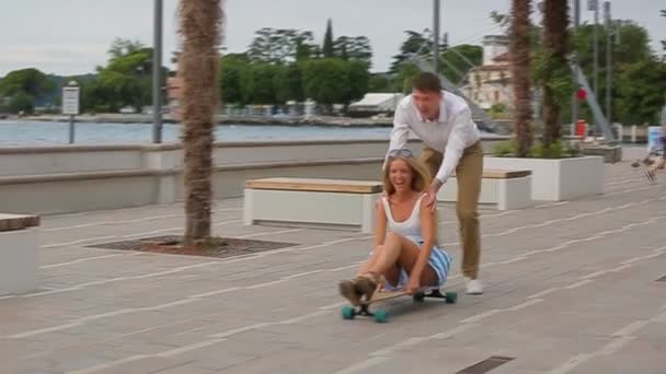 Young happy couple in love sitting on a skateboard - Video