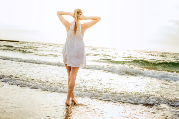 молода красива біла жінка насолоджується сонцем на пляжі під час сходу або заходу сонця
 - Фото, зображення