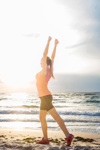 Fitness urheilumalli tekee harjoituksia ulkoilun aikana auringonnousun aikaan. Kaunis valkoihoinen nainen koulutus ulkona meren rannalla aamulla
 - Valokuva, kuva