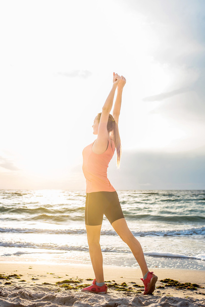 Fitness urheilumalli tekee harjoituksia ulkoilun aikana auringonnousun aikaan. Kaunis valkoihoinen nainen koulutus ulkona meren rannalla aamulla
 - Valokuva, kuva