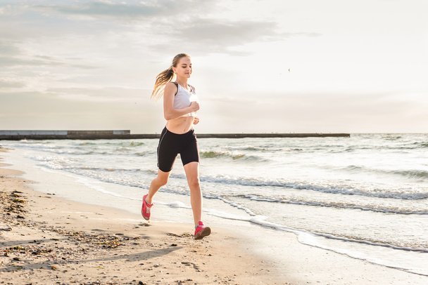 Fitness spor modeli gündoğumu üzerinde açık çalışması sırasında egzersizleri yapıyor. Güzel beyaz kadın eğitim dışında sahil sabah - Fotoğraf, Görsel
