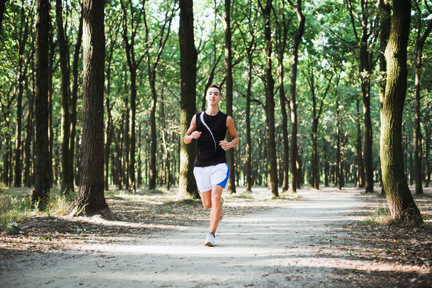 young caucasian male running in park. Teenager jogging in park - 写真・画像