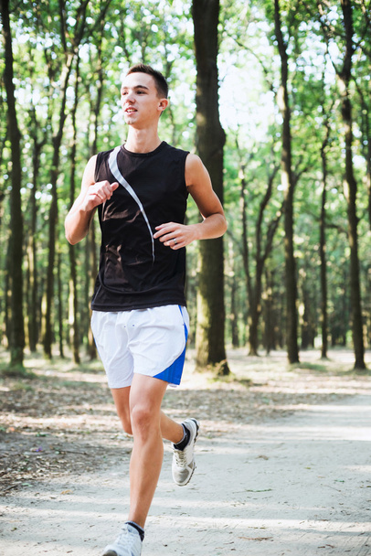 young caucasian male running in park. Teenager jogging in park - Foto, imagen