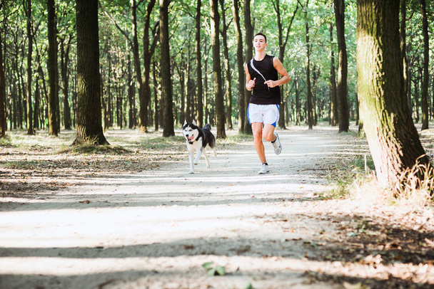 work out with dog. Young caucasian male running with siberian hu - Foto, Bild