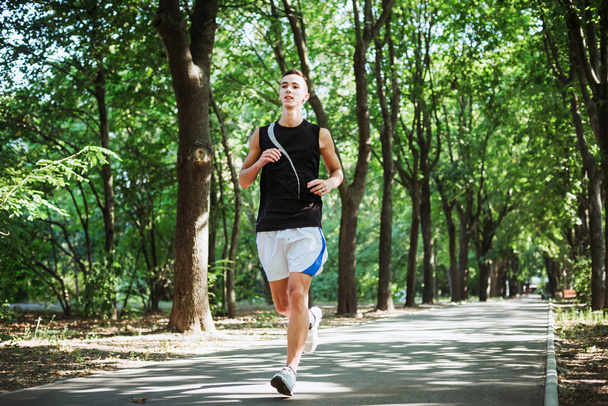 young caucasian male running in park. Teenager jogging in park - Foto, Imagen