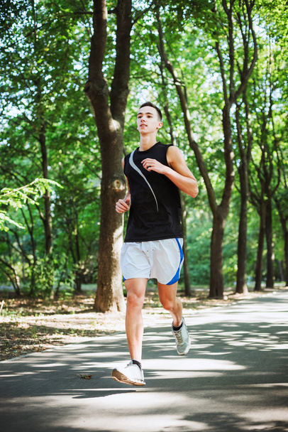 young caucasian male running in park. Teenager jogging in park - Photo, Image