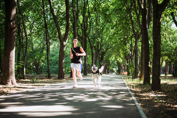 work out with dog. Young caucasian male running with siberian hu - Fotoğraf, Görsel