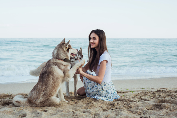 young caucasian female playing and having fun with siberian husky dog on beach - Foto, Imagen