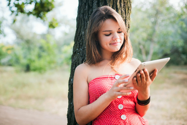 young beautiful caucasian female using tablet in park - 写真・画像
