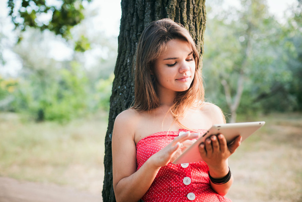 young beautiful caucasian female using tablet in park - 写真・画像